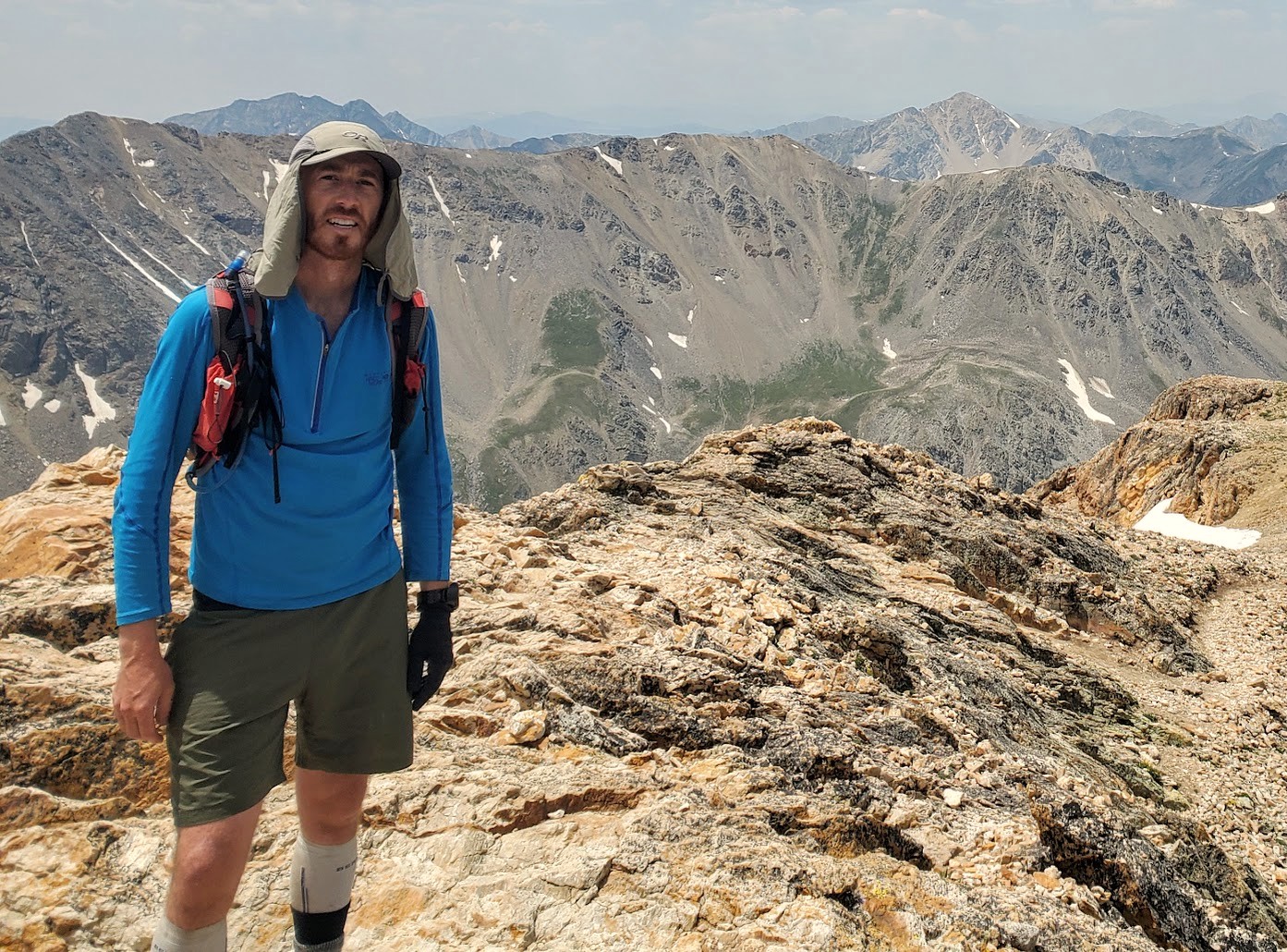 Dan standing on a rocky 14er summit with the Sangre de Cristo range behind him