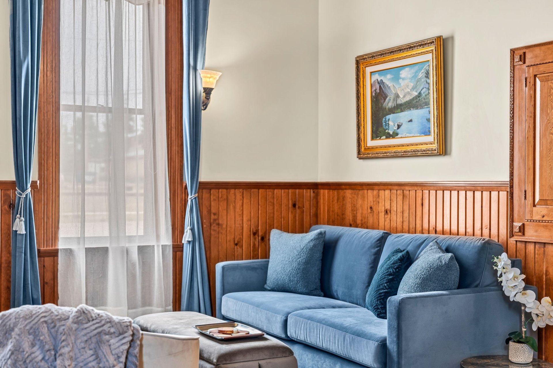 Guest sitting area with mountain painting and blue velvet sofa